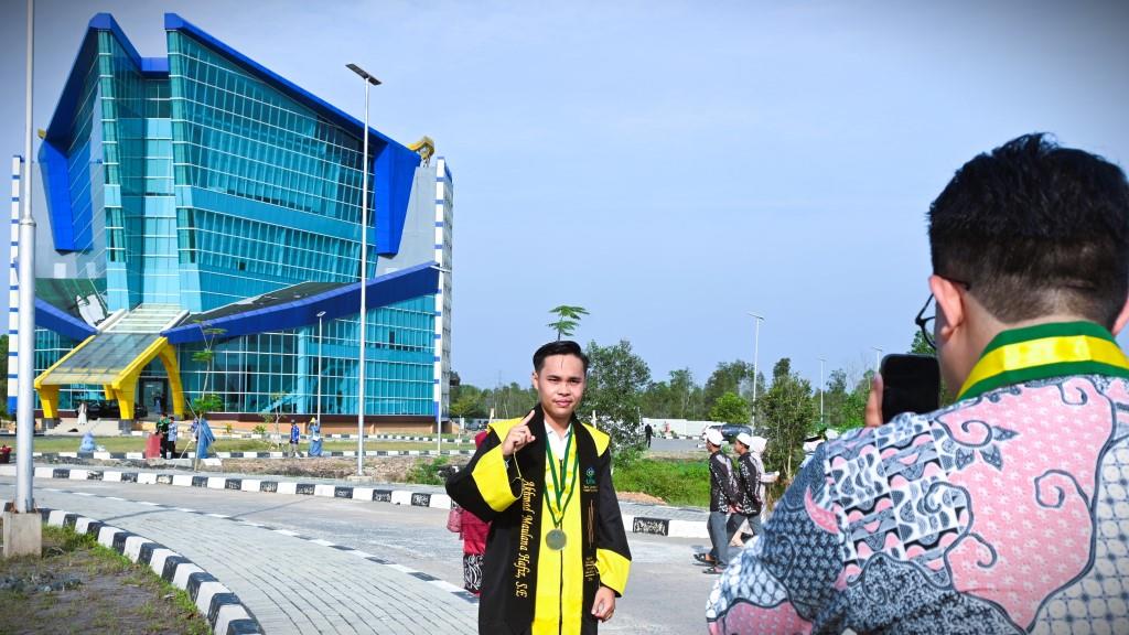 Akhmad Maulana Hafiz, S.E. saat berfoto berlatar Gedung Rektorat Kampus 2 (Foto Humas Jamal Ripani)