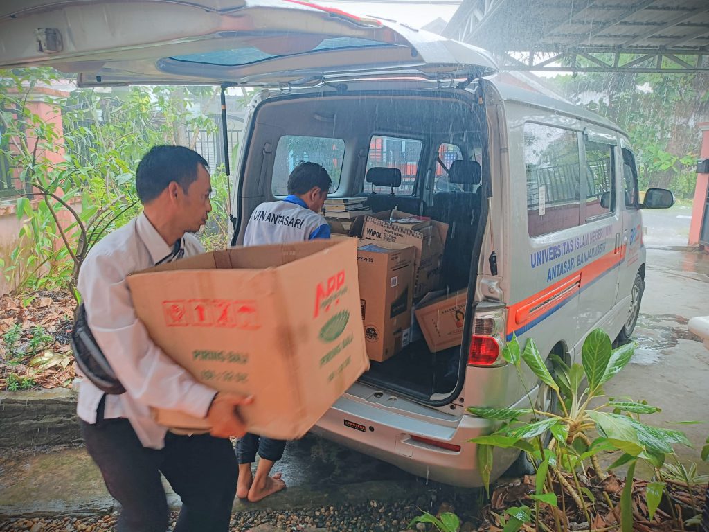 Tak terhalang hujan, Nasrullah HY bersama Muhammad Alwi tetap semangat membantu pengangkutan sumbangan buku.