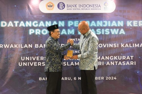 Rektor UIN Antasari Banjarmasin, Prof. Dr. H. Mujiburrahman menyerahkan plakat UIN Antasari Banjarmasin berlatarkan gedung transformer berwarna emas. (Foto:Humas/Baiti Rahmi)