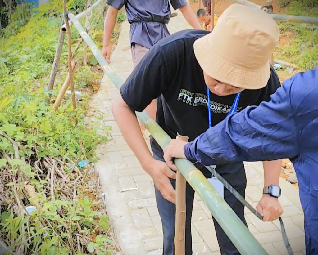 Mahasiswa KKN UIN Antasari saat membantu membuatkan pegangan jalan terjal menuju musala.